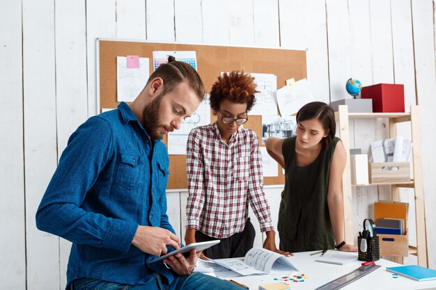 Collega's glimlachen, spreken, bespreken tekeningen, nieuwe ideeën