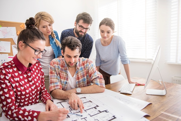 Collega's op kantoor met architectuurplannen en een computer