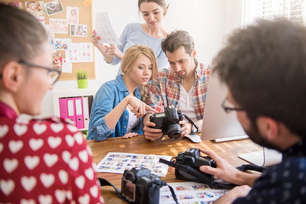 Gratis foto collega's op kantoor met fotocamera's en een computer