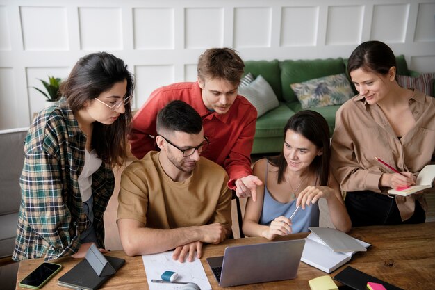 Collega's op zoek naar informatie met behulp van een laptop en notebooks in een studiesessie