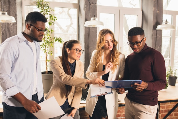 Collega's werken samen in een modern kantoor met behulp van apparaten en gadgets tijdens onderhandelingen