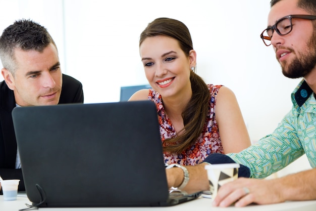 Collega&#39;s zitten met tafel en met behulp van laptop