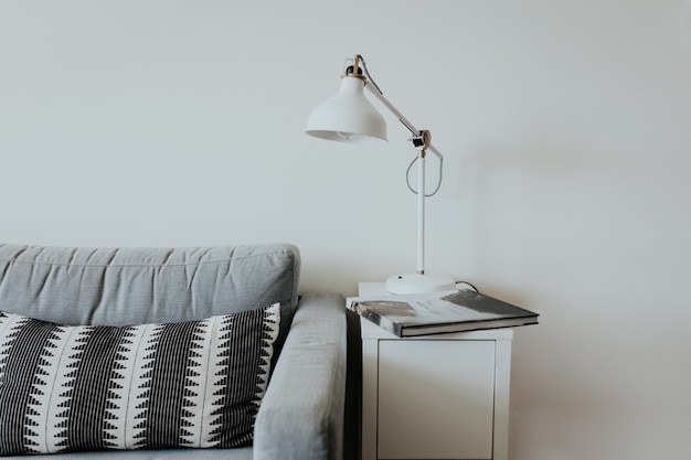 Gratis foto comfortabele bank in een modern huis met een lamp op een kleine witte plank en een boek met een waterval