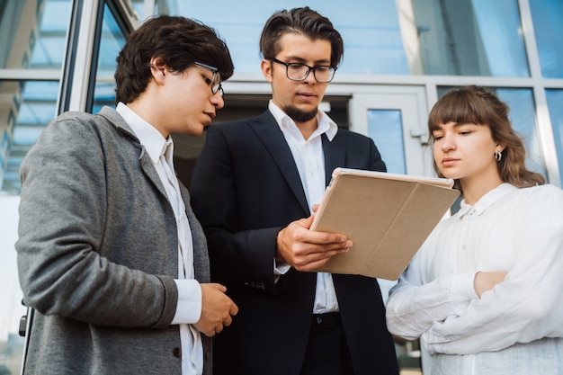 Commercieel team twee mannen en vrouw die buiten samenwerken.