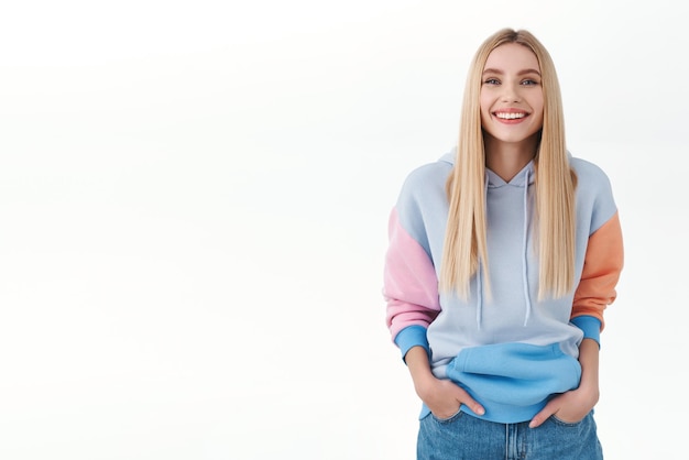 Communicatie, jeugd en lifestyle concept. Aantrekkelijk jong meisje met lang blond haar, stralende glimlach met witte tanden