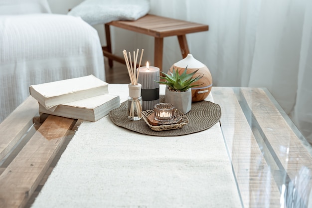 Compositie met wierookstokjes, diffuser, kaarsen en boeken op de tafel in het interieur van de kamer.