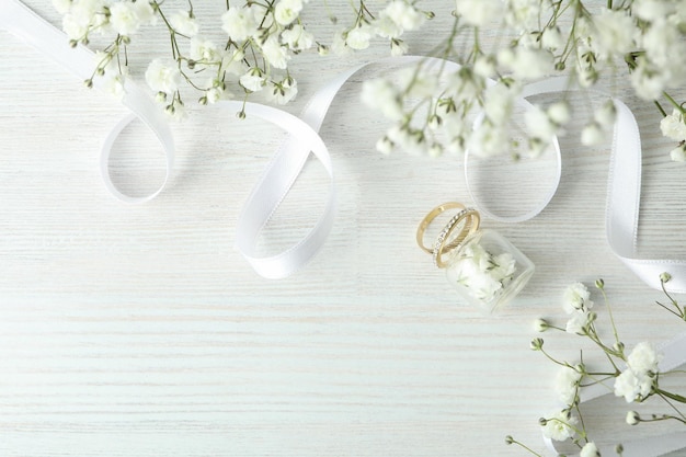 Concept huwelijkstoebehoren met trouwringen op witte houten achtergrond