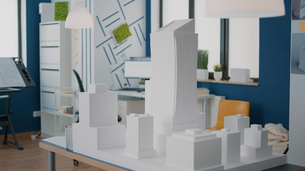 Concept van bouwmodel en constructieontwerp op tafel op lege werkplek. Maquette en stedenbouwkundig plan gebruikt voor vastgoedontwikkeling. Architecturale blauwdrukken structuur.