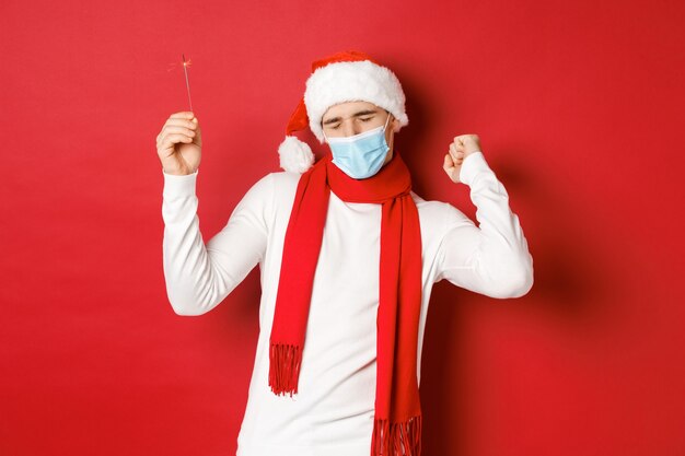 Concept van covid kerst en feestdagen tijdens pandemische gelukkige man die nieuwjaar viert op feestkleding...