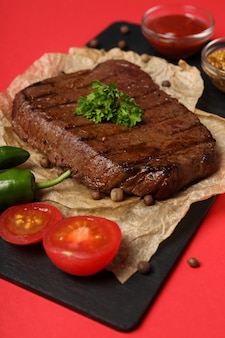 Concept van lekker eten met biefstuk op rode achtergrond