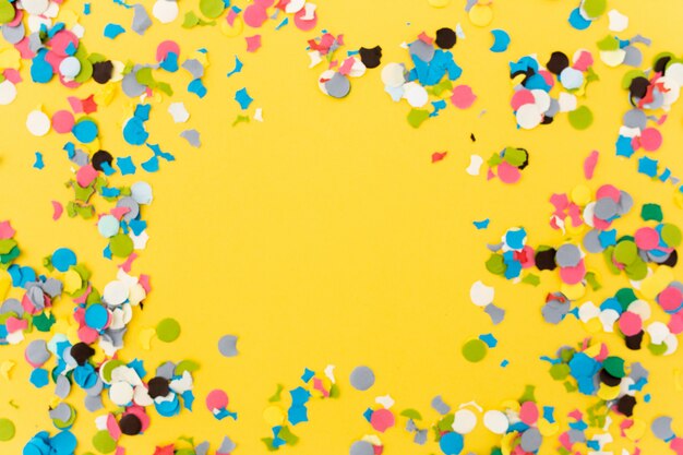 Confetti op gele achtergrond na het beëindigen van het feest