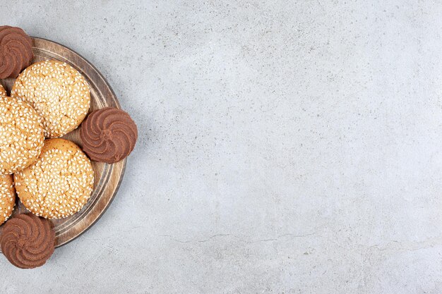 Cookies netjes gestapeld op een houten bord op marmeren achtergrond.