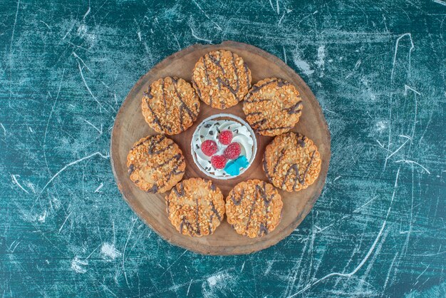 Cookies rondom een cupcake op een houten bord op blauwe achtergrond. Hoge kwaliteit foto