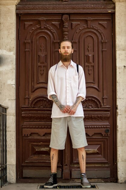 Cool hipster in wit overhemd poseren voor een deur. Stijl en diversiteit