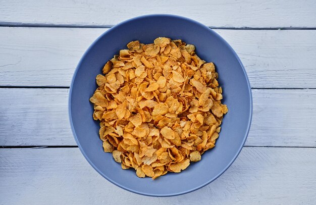 Cornflakes in een bord op een houten bureau. Voedselconcept