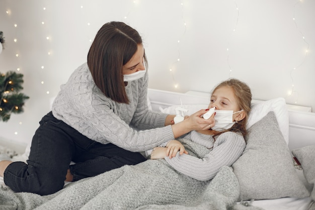 Coronavirus bij een kind. Moeder met dochter. Kind liggend in een bed. Vrouw in een medisch masker.