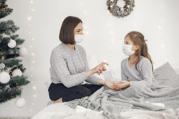 Coronavirus bij een kind. Moeder met dochter. Kind liggend in een bed. Vrouw in een medisch masker.