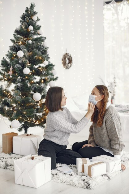 Coronavirus en kerstconcept. Vrouw helpt haar vriend met een masker.