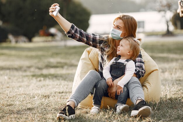 Coronavirus-thema. Familie in een zomerpark. Vrouw in een celoverhemd.