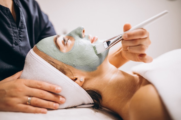 Cosmetologist die masker op een gezicht van cliënt toepast in een schoonheidssalon