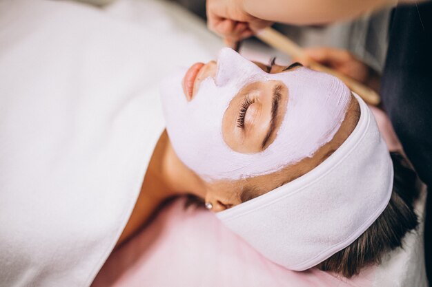 Cosmetologist die masker op een gezicht van cliënt toepast in een schoonheidssalon