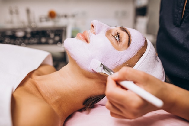Cosmetologist die masker op een gezicht van cliënt toepast in een schoonheidssalon