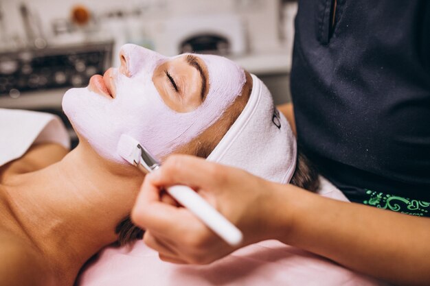 Cosmetologist die masker op een gezicht van cliënt toepast in een schoonheidssalon