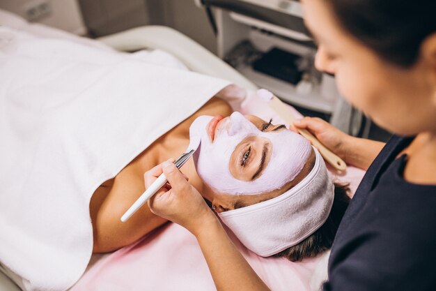 Cosmetologist die masker op een gezicht van cliënt toepast in een schoonheidssalon