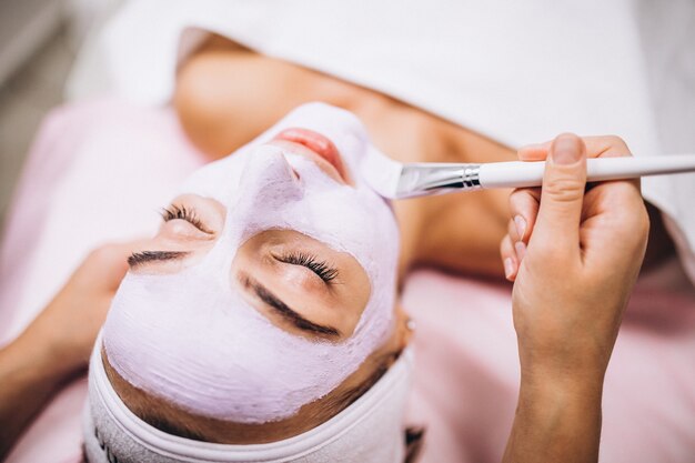 Cosmetologist die masker op een gezicht van cliënt toepast in een schoonheidssalon
