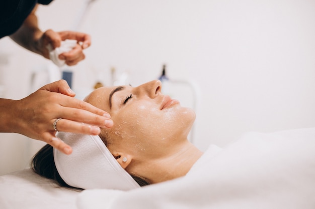 Cosmetologist schoonmakend gezicht van een vrouw in een schoonheidssalon