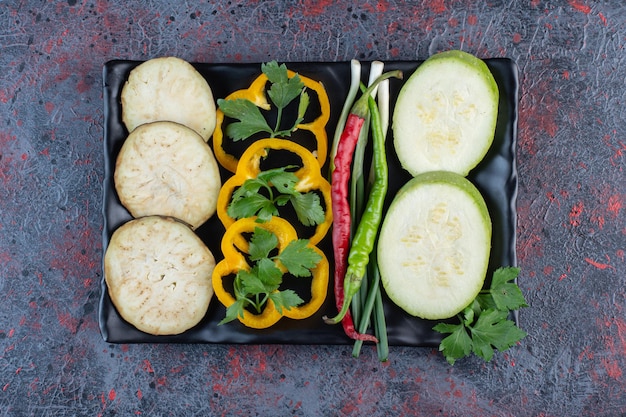 Courgette, aubergine en paprika plakjes met hete pepers en lente-uitjes op een schotel op donker gekleurde achtergrond. Hoge kwaliteit foto