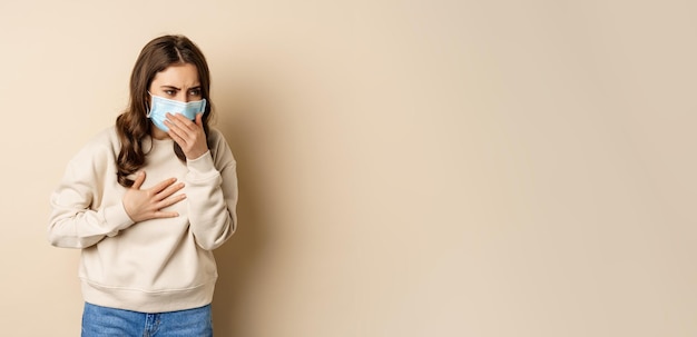 Covid en gezondheidsconcept zieke vrouw met medisch gezichtsmasker hoestend ziek voelen met zure keel stand