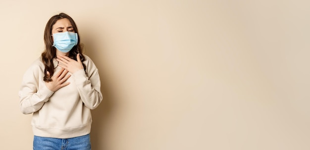 Covid en gezondheidsconcept zieke vrouw met medisch gezichtsmasker hoestend ziek voelen met zure keel stand