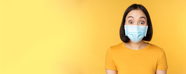 Covid en medisch concept close-up portret van aziatische vrouw in gezichtsmasker die verrast en verbaasd kijkt