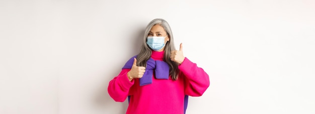 Covid-pandemie en sociaal afstandsconcept vrolijke en stijlvolle aziatische oudere vrouw die medisch draagt