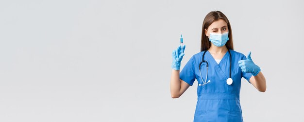 Covid19 preventie van virusgezondheid gezondheidswerkers en quarantaineconcept Vriendelijke vrouwelijke verpleegster of arts in blauwe scurbs knipoogt persoonlijke beschermingsmiddelen en verzekert dat het nodig is een vaccin te maken