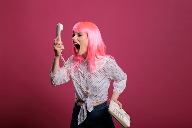 Crazy funky persoon schreeuwen op vaste telefoongesprek op camera, poseren en praten op retro vintage telefoon. Een gesprek op afstand hebben met een vaste snoertelefoon, trendy vrouw in de studio.