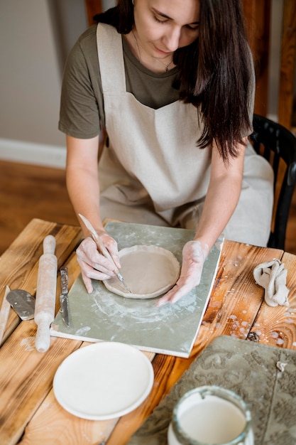 Creatieve vrouw die een aarden pot maakt in haar atelier