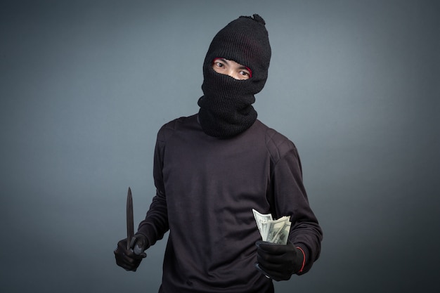 Gratis foto criminelen dragen een zwart masker en houden donker op grijs