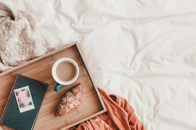 Croissant en koffie dichtbij boek op bed