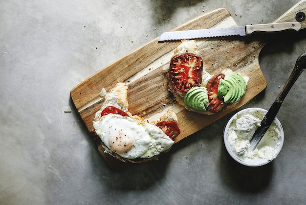 Gratis foto croissant met heirloom tomaat, avocado en een gebakken ei