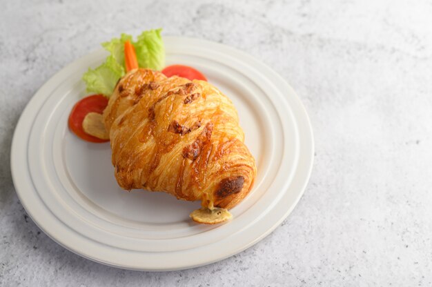 Croissant met hotdog op witte schotel