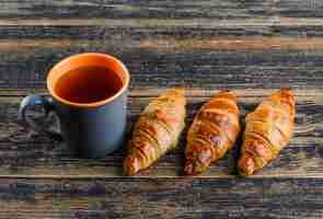 Gratis foto croissant met mening van de kop thee de hoge hoek over een houten lijst