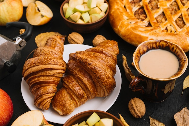 Croissants en koffie dichtbij appelen en pastei