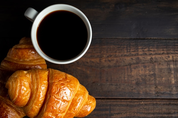 croissants en koffie op oude houten tafel.