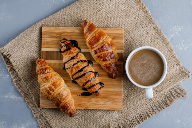Croissants met koffie, houten stuk plat lag op gips en stuk zak