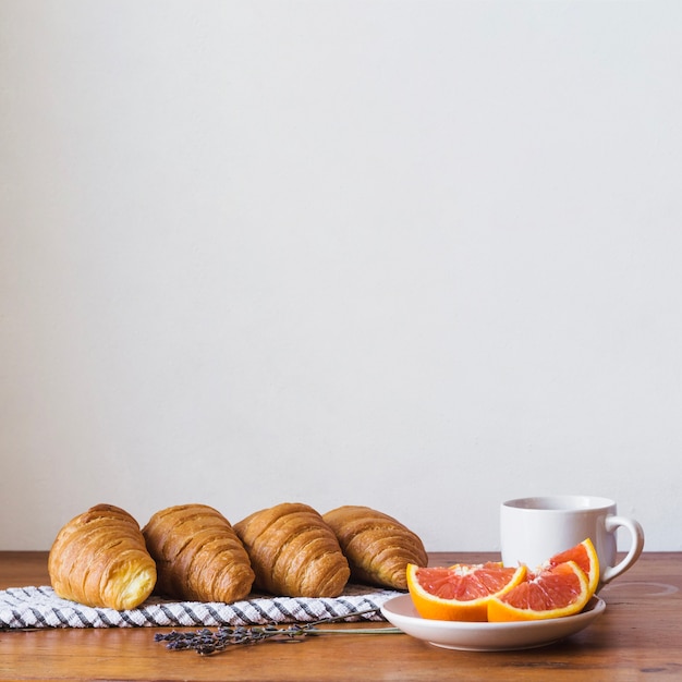 Gratis foto croissants met sinaasappels en beker