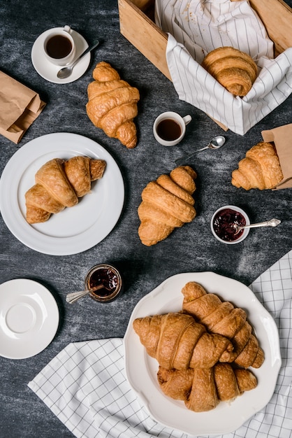 croissants, pot met jam en koffiekopje opzij op grijze tafel