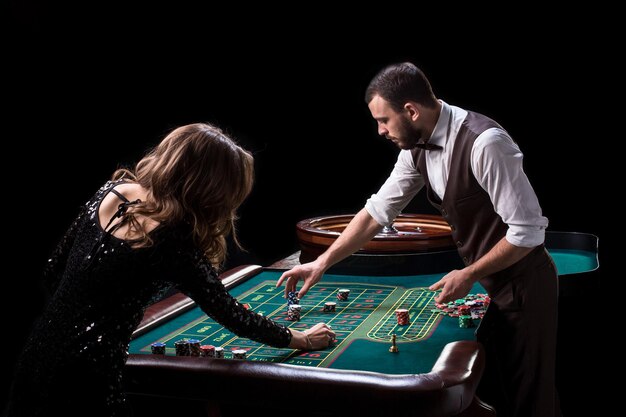 Croupier en vrouwelijke speler aan een tafel in een casino. Afbeelding van een klassiek casino roulette wiel. Gokken. Casino. Roulette. Poker