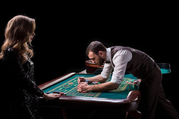 Croupier en vrouwelijke speler aan een tafel in een casino. Afbeelding van een klassiek casino roulette wiel. Gokken. Casino. Roulette. Poker
